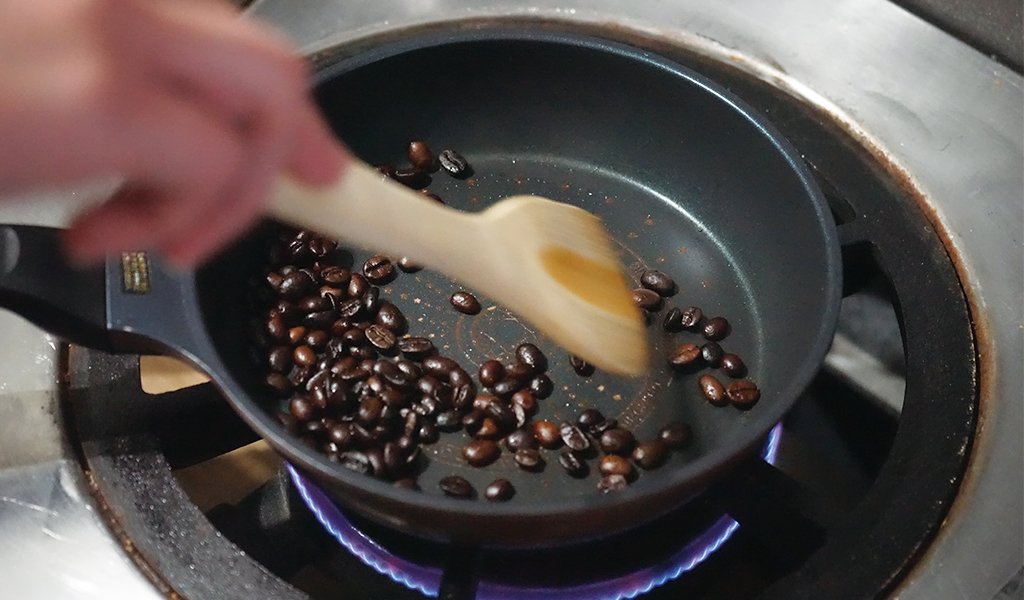茹でたコーヒー豆を木べらを使って炒める