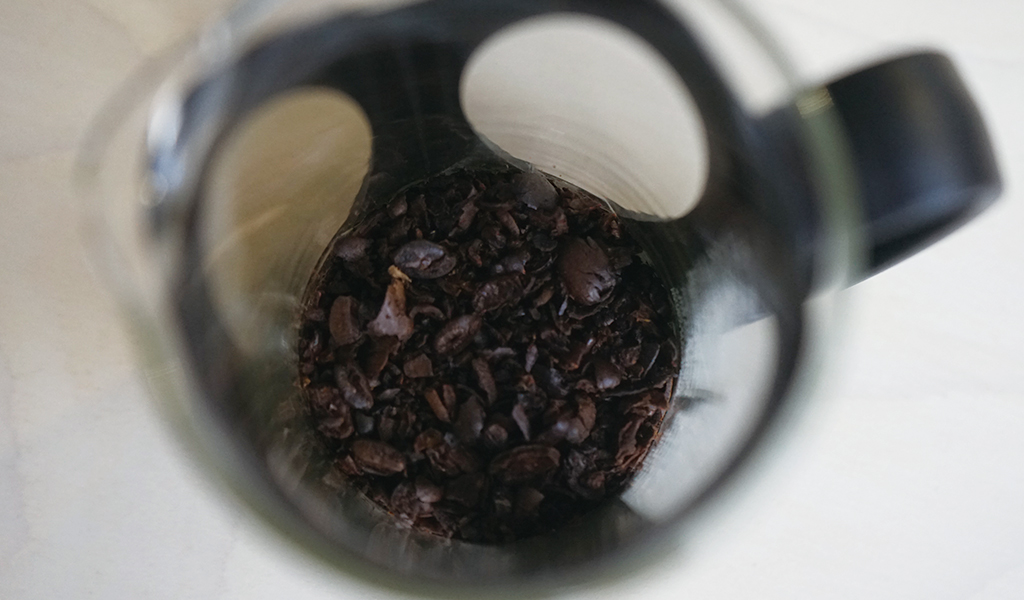茹でたコーヒー豆を挽く